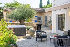 a patio with a hot tub and chairs and a tree at Secret d'Uzès - Le Duché - Piscine chauffée et Jacuzzi in Uzès +36 photos