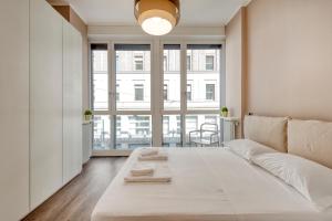 Duomo Apartments B Home - Panoramic Two Bedrooms Apt في ميلانو: سرير أبيض في غرفة مع نافذة كبيرة +5 صور