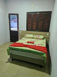 a bedroom with a bed with a red blanket on it at Pousada Encantos de Paripueira in Paripueira