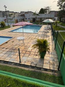 a fence around a pool with a table and an umbrella at Pérola da Amazônia AP Aconchegante, Vista Floresta in Marituba