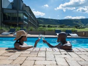 two people sitting next to a swimming pool at ANEW Resort Vulintaba Newcastle in Newcastle
