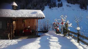 a cabin covered in snow with a fence and trees at Garni Waldeck in San Giacomo