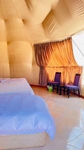 a bedroom with a bed and two chairs and a window at wadi rum planet camp in Disah +58 photos