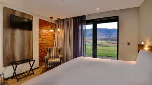 a bedroom with a bed and a chair and a window at ANEW Resort Vulintaba Newcastle in Newcastle
