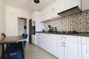 een witte keuken met witte kasten en blauwe stoelen bij Smart Stay Plaza in Boekarest