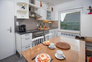 a kitchen with a wooden table and a dining room at Seewind in Krummhörn