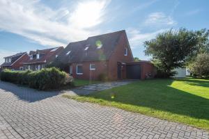 a red brick house with a driveway in a yard at Seewind in Krummhörn