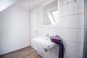 a white bathroom with a sink and a window at Seewind in Krummhörn +41 photos