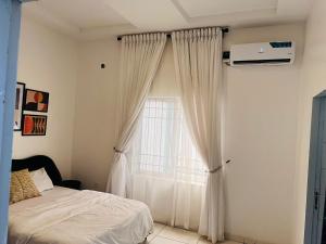 a bedroom with a bed and a window with curtains at Bytup 2bedroom Apt in lekki,24hrs light, Wifi ,fully serviced apartment , water heater smart tv in Lekki