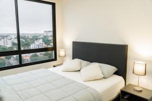 a bedroom with a white bed with a large window at Departamento de lujo en zona Carmelitas in Asuncion +43 photos