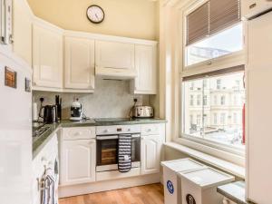 a kitchen with white cabinets and a clock on the wall at Buoy On The Bay in Bridlington
