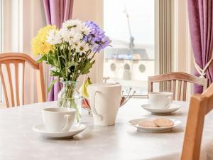 a table with a vase of flowers and two cups at Buoy On The Bay in Bridlington