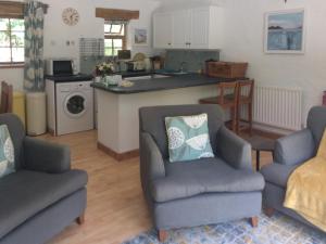 a living room with two chairs and a kitchen at Oaktree Cottage in Appledore