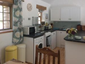 a kitchen with white cabinets and a stove top oven at Oaktree Cottage in Appledore +9 photos