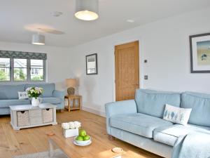 a living room with a blue couch and a table at Oakwood in Saint Endellion
