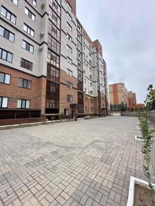une cour vide devant de grands bâtiments dans l'établissement Уютная 1 комнатная квартира в ЖК БАВАРИЯ, à Aqtöbe