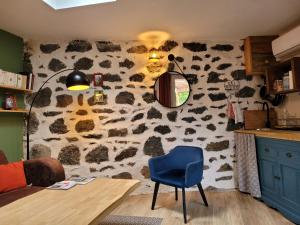 a room with a stone wall with a table and a blue chair at La maisonnette sous le cerisier in Bergonne