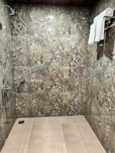 a bathroom with a stone wall with a shower at Nicolas Farm & Resort in Mansar +69 photos