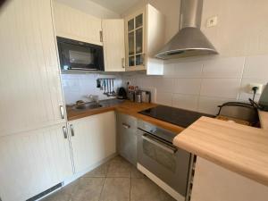 a kitchen with white cabinets and a sink at Appartement au face port avec grande terrasse in Audierne