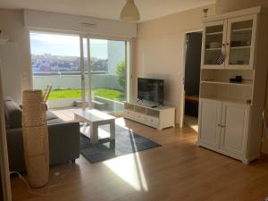 a living room with a couch and a television at Appartement au face port avec grande terrasse in Audierne