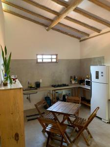 Una cocina con una mesa y un refrigerador blanco. en Casa e Chalé raio de sol, en Caraíva