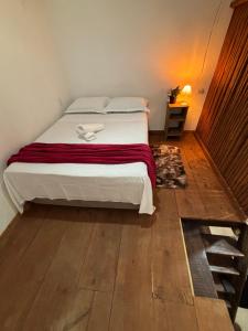 a bedroom with a bed and a wooden floor at Casa e Chalé raio de sol in Caraíva