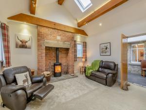 a living room with leather chairs and a fireplace at Clarion Lodge Cottage Ilkley in Menston