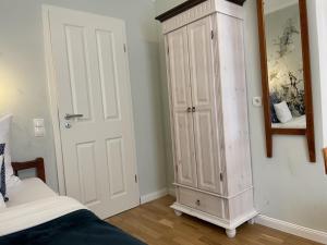 a bedroom with a white cabinet next to a bed at Hotel Söruper Hof in Sörup