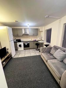 a living room with a couch and a kitchen at Cozy modern 2 bedroom apartment with comfortable lounge in Preston