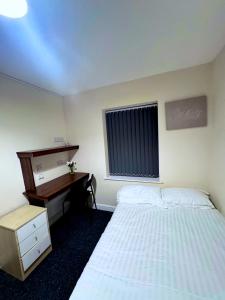 a bedroom with a bed and a desk and a window at Cozy modern 2 bedroom apartment with comfortable lounge in Preston