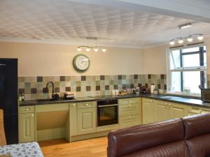 una cocina con armarios verdes y un reloj en la pared en The Granary - Uk47428, en Bewaldeth