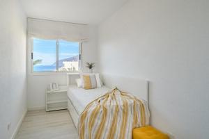 a white bedroom with a bed and a window at Playa La Arena 2 Bed Apartment in Puerto de Santiago