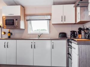 Una cocina con gabinetes blancos y una ventana. en To The Brink - Uk50394, en Great Billing