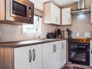 Una cocina con gabinetes blancos y un microondas. en To The Brink - Uk50394, en Great Billing
