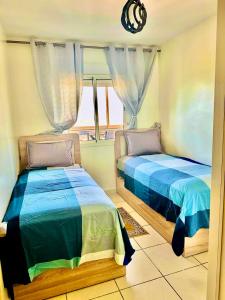 two beds in a room with a window at Apprt cosy près plage des Nations in Salé