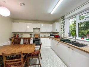 a kitchen with white cabinets and a wooden table at Croftfoot in Arnisdale