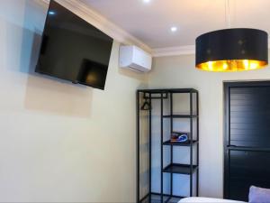 una camera con TV a parete e mensola di Wild Olive Luxury Accommodation a Hutton Heights