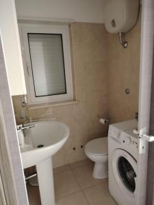 a bathroom with a toilet sink and a washing machine at La Casetta di Bea in Bernalda