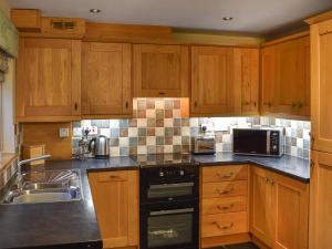 eine Küche mit Holzschränken und einer Spüle in der Unterkunft Penny Rigg Cottage in Coniston