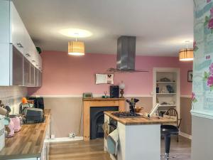 a kitchen with pink walls and a stove top oven at Rosslyn in Evanton