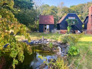 a blue house with a pond in front of it at Wysteria, North Lodge in Rusper
