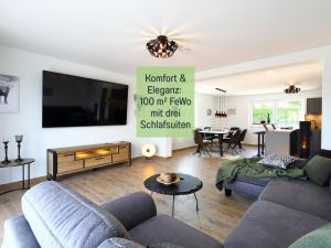 诺特海姆Ferienhaus Höckelheim - Savanna Lodge - barrierefrei - 3 Schlafzimmer-bis 6 Gäste - nahe Göttingen - 100 qm - Babies reisen gratis - Terrasse, Garten & Grill - vollausgestattete Küche mit Spülmaschine - Klimaanlage, Fußbodenheizung & Raffstores的客厅里有一张沙发和一台电视