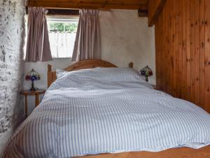 a bed with a blue and white striped comforter in a bedroom at Skyber - Uk50374 in Camelford