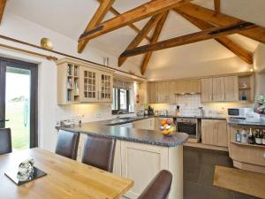 a large kitchen with wooden cabinets and a table at The Linhay in Little Petherick