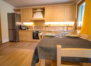 a kitchen with a table with chairs and a refrigerator at Nido Alpino - Nel cuore delle Dolomiti in Pieve di Cadore