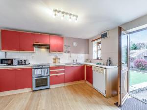 eine Küche mit roten Schränken und einem großen Fenster in der Unterkunft The Cottage - 28645 in Alston