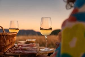 two glasses of wine sitting on a table with a basket at Prairie de la Gervanne - Panorama Drôme & Vercors in Beaufort-sur-Gervanne