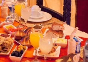 a table with plates of food and glasses of orange juice at Sahara Crown Luxury Camp in Merzouga