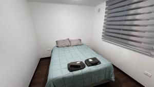 a small bedroom with a bed with two bags on it at Acogedor departamento en La Serena in La Serena