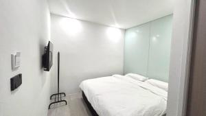 a white room with a bed and a mirror at 65 Hostel Bangkok in Bangkok Noi
